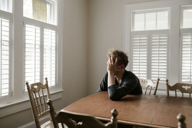 photo of depressed man leaning on wooden table